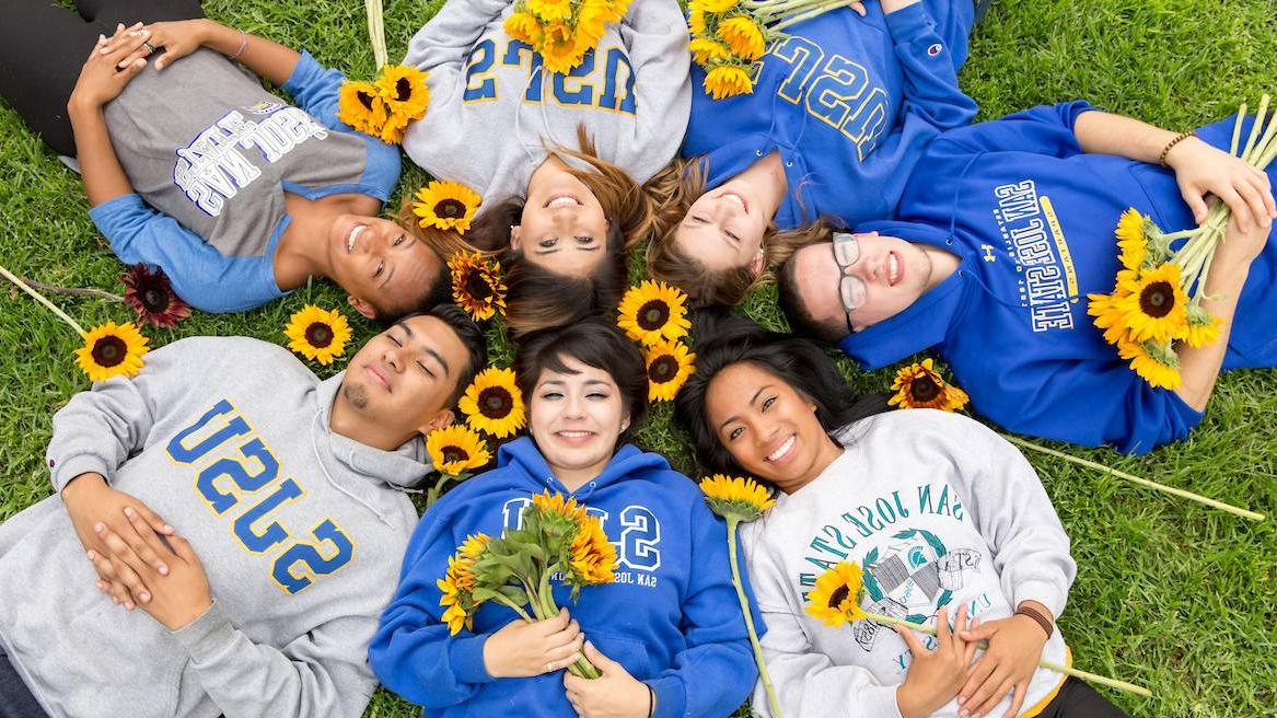 happy smiling students laying on grass